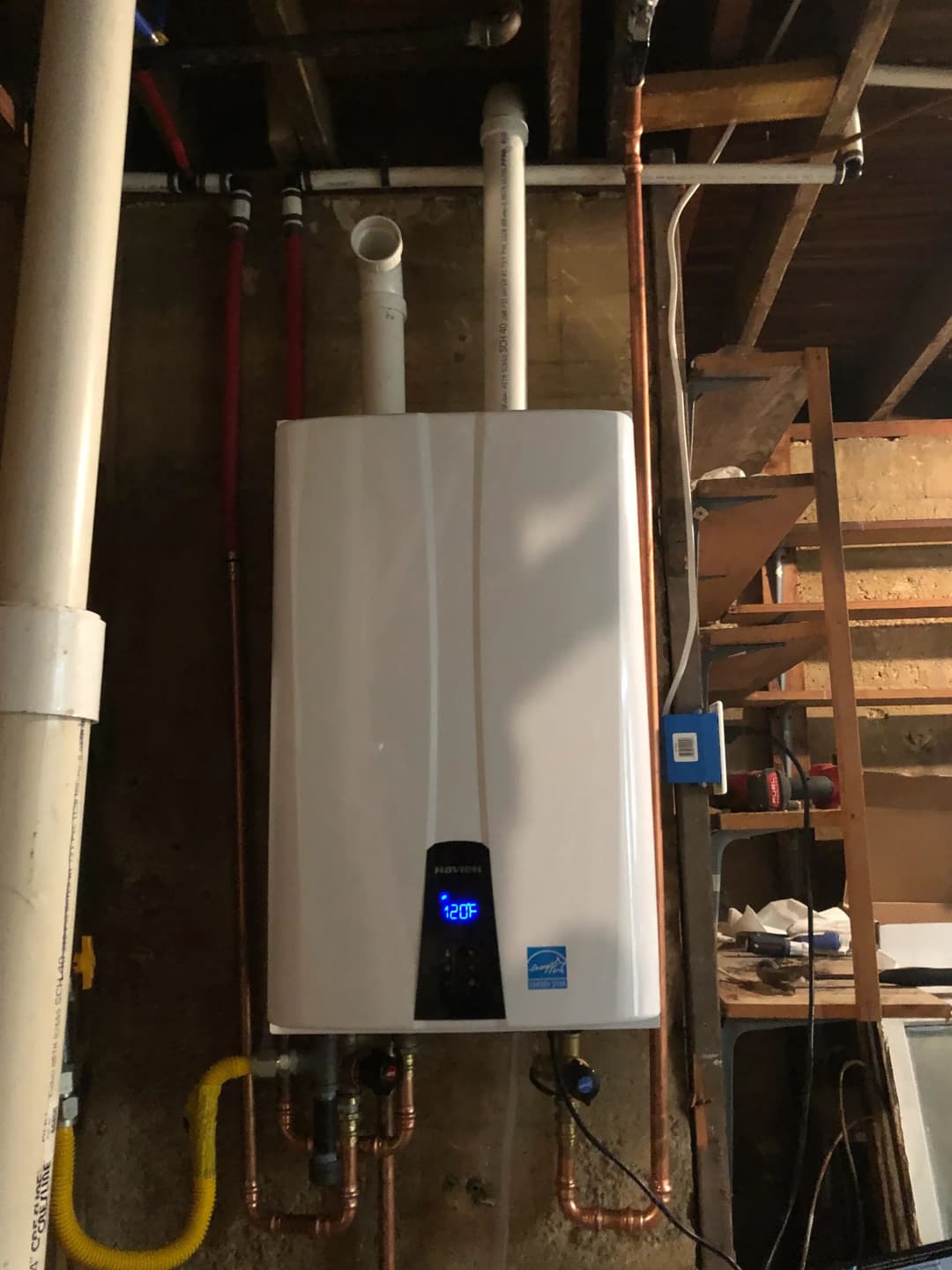 Tankless water heater mounted on a wall with visible pipes and digital temperature display.