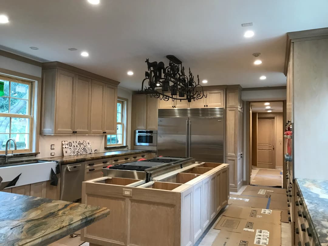 Modern kitchen with wood cabinets, large island, stainless steel appliances, and chandelier.