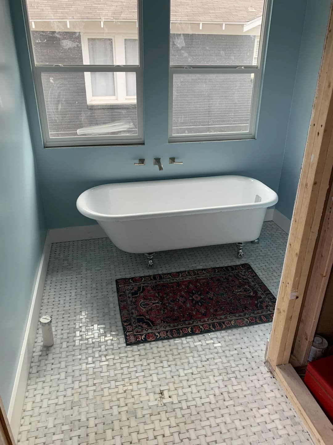 Modern bathroom featuring a freestanding white bathtub and mosaic tiled flooring.