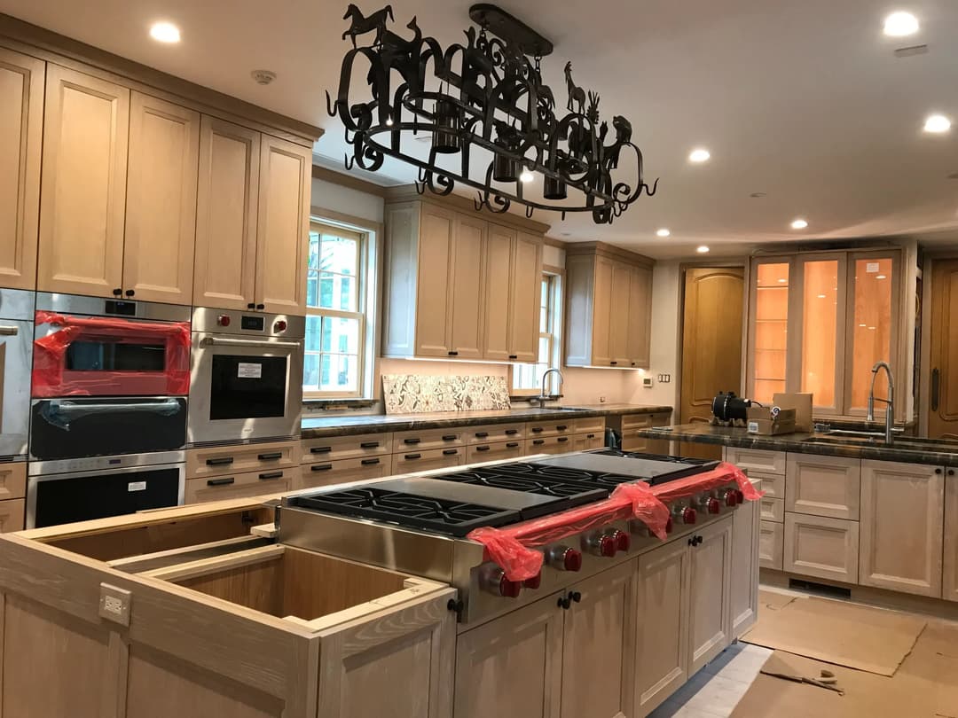 Modern kitchen renovation featuring a large island, stainless steel appliances, and wooden cabinets.