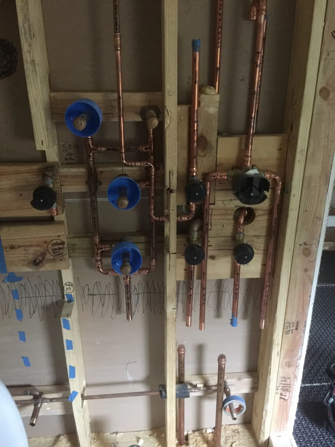 Copper plumbing installation on wooden framework, showcasing pipes and fittings.