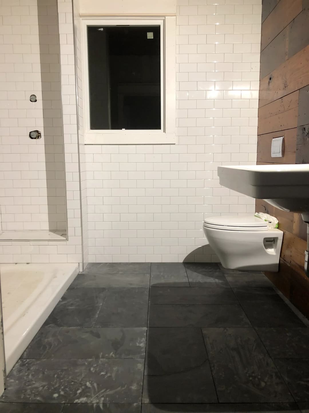 Modern bathroom with white subway tiles, a shower area, toilet, and slate tile floor.