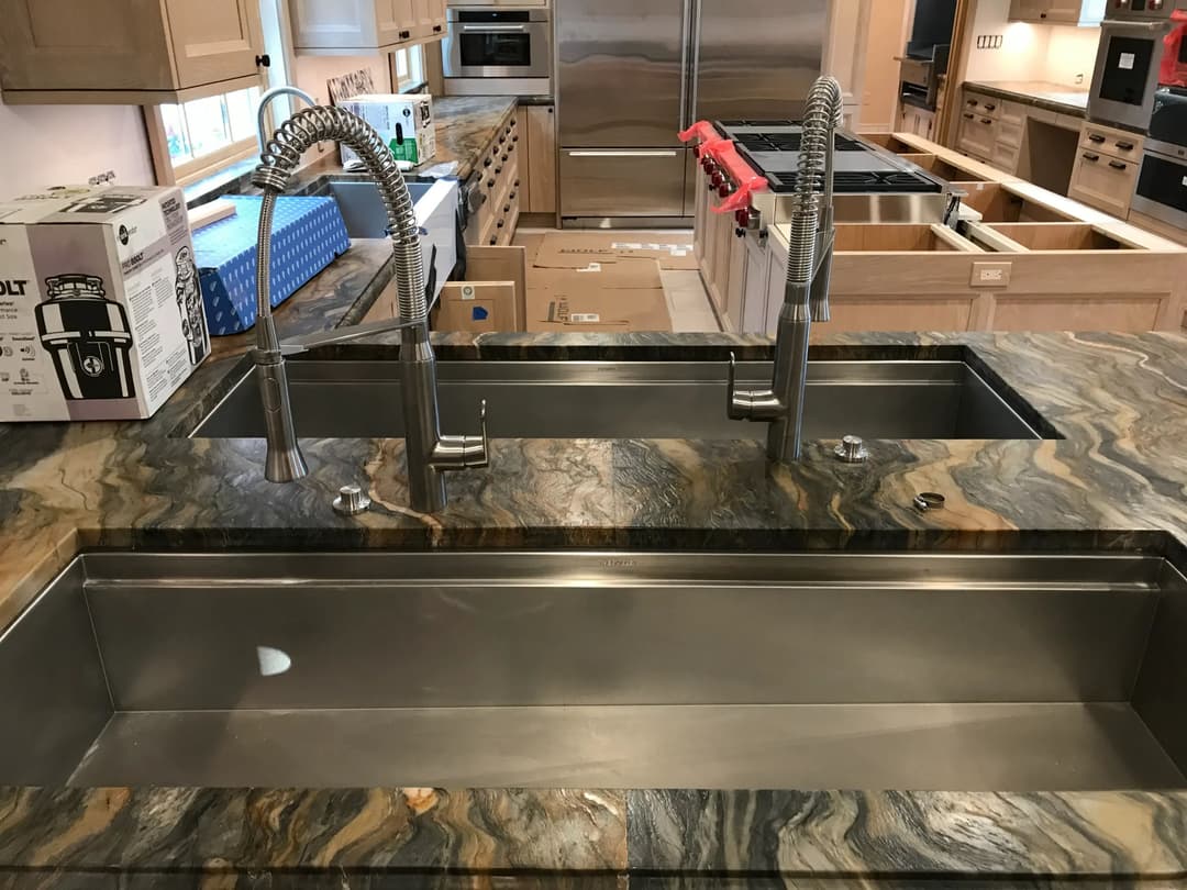 Double stainless steel sinks on a granite countertop in a modern kitchen remodel.