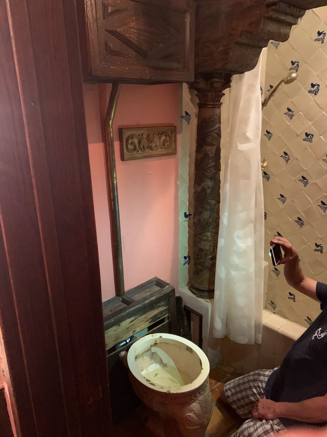 Bathroom featuring an ornate column, unique toilet design, and decorative wallpaper.