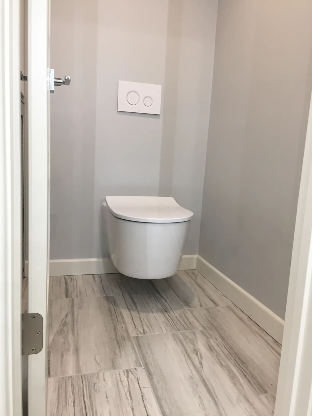 Modern bathroom featuring a wall-mounted toilet in a minimalist design with gray walls.