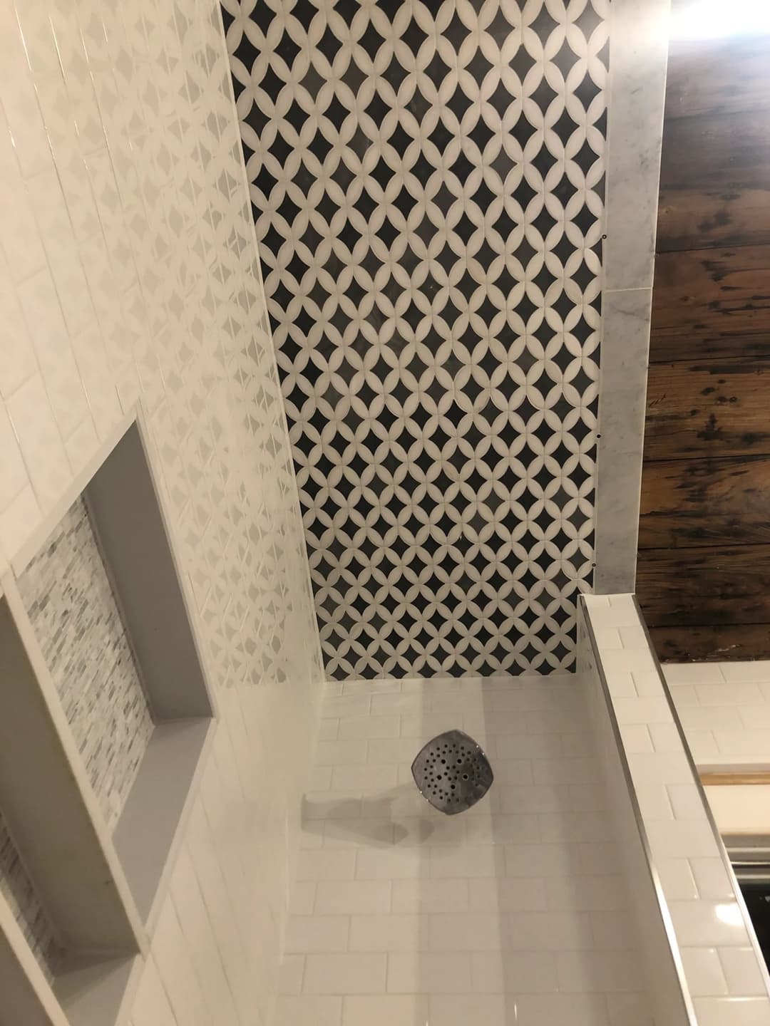 Stylish bathroom ceiling with patterned tiles and modern showerhead design.