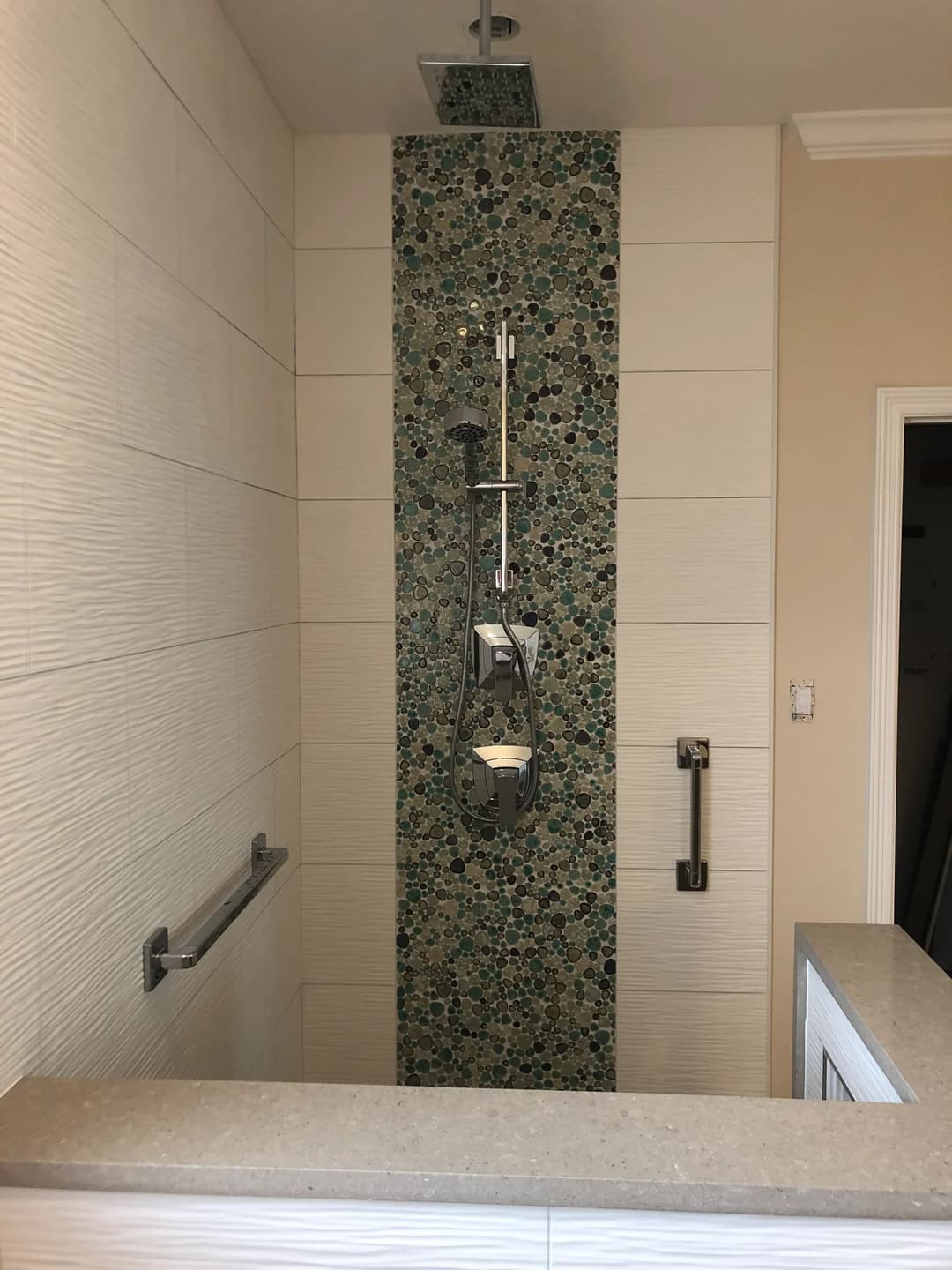 Modern shower featuring a unique pebble accent wall and minimalist design.